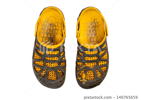 dirty paint stained and heavily worn yellow black rubber sandals or shoes with perforated design, top view dirty paint stained and heavily worn yellow black rubber sandals or shoes with perforated design, top view 140765659