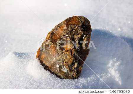 Hand-knapped primitive flint tool replica rests on sparkling pristine snow under bright sun. Ancient Paleolithic craftsmanship artifact Hand-knapped primitive flint tool replica rests on sparkling pristine snow under bright sun. Ancient Paleolithic craftsmanship artifact 140765680