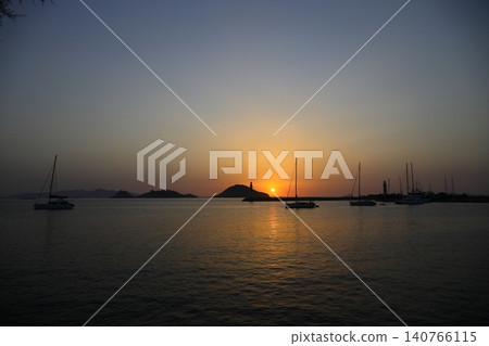 Seascape at sunshine. Lighthouse and sailings on the coast. Seaside town of Turgutreis and spectacular sunshine Seascape at sunshine. Lighthouse and sailings on the coast. Seaside town of Turgutreis and spectacular sunshine 140766115