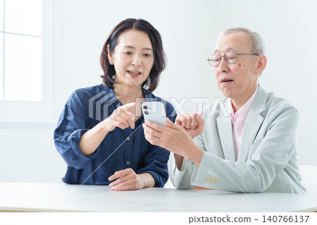 一位老人正在學習如何使用智慧型手機。 一位老人正在學習如何使用智慧型手機。 140766137
