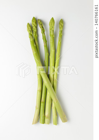 A top-down photograph of five asparagus spears lined up against a white background. A top-down photograph of five asparagus spears lined up against a white background. 140766161