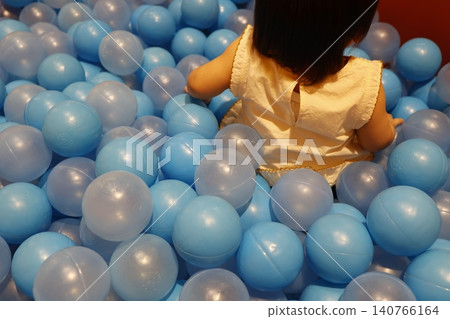 A part of the body of a one-year-old toddler playing in a blue ball pit. Indoor playground. A part of the body of a one-year-old toddler playing in a blue ball pit. Indoor playground. 140766164