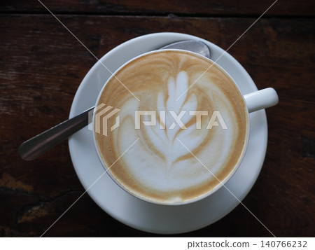 Coffee cup, latte art, saucer, spoon on dark wooden table in cafe Coffee cup, latte art, saucer, spoon on dark wooden table in cafe 140766232