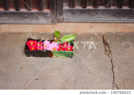 Camellias adorning the eaves of an old Japanese house. The red flowers floating in ceramic vases add a touch of traditional Japanese charm. Camellias adorning the eaves of an old Japanese house. The red flowers floating in ceramic vases add a touch of traditional Japanese charm. 140766635