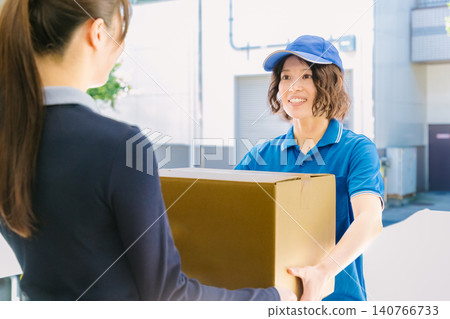 A female delivery person and a woman receiving a package. A female delivery person and a woman receiving a package. 140766733