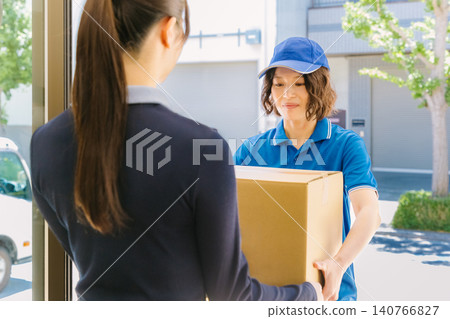 一名女送貨員和一名收包裹的女士。 一名女送貨員和一名收包裹的女士。 140766827