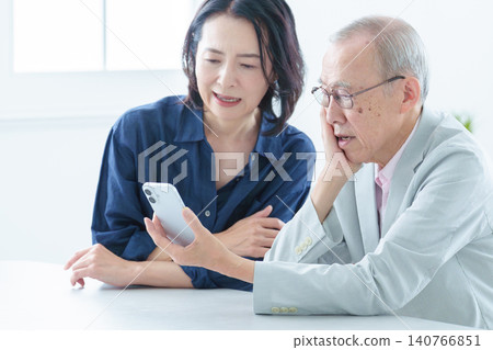 An elderly man with a troubled expression learns to use a smartphone. An elderly man with a troubled expression learns to use a smartphone. 140766851