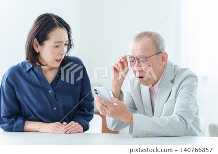 An elderly man with a troubled expression learns to use a smartphone. An elderly man with a troubled expression learns to use a smartphone. 140766857