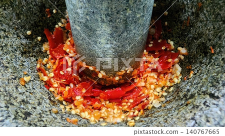 Pounding Red Chili Peppers in Traditional Stone Mortar and Pestle Pounding Red Chili Peppers in Traditional Stone Mortar and Pestle 140767665