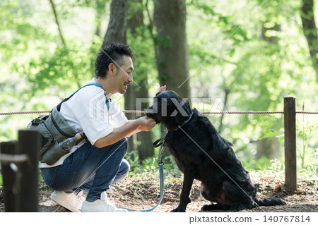 一個男人喜歡遛狗和與狗互動;喜歡在公園裡訓練大型犬;喜歡零食。 一個男人喜歡遛狗和與狗互動;喜歡在公園裡訓練大型犬;喜歡零食。 140767814