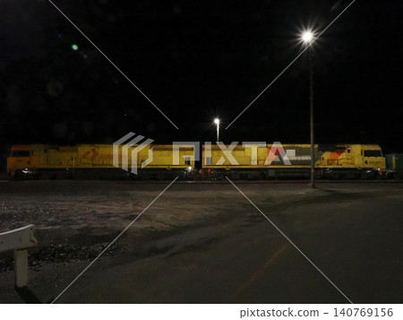 Two locomotives stand side-by-side in the grounds of Broken Hill Station in Australia—the nighttime lighting illuminates the quiet presence of the railway. Two locomotives stand side-by-side in the grounds of Broken Hill Station in Australia—the nighttime lighting illuminates the quiet presence of the railway. 140769156