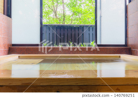 家庭浴室裡擺放著柏木浴缸，牆上掛著溫泉的靜物照片。 140769251