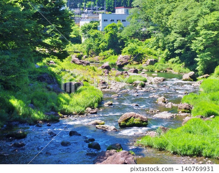 A beautiful, rocky, clear stream surrounded by lush green mountains. 140769931