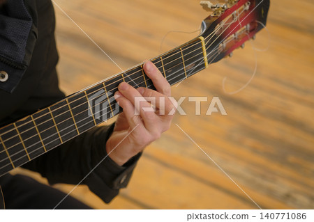 The musician clamps the strings on the neck of the guitar, close-up, focus on the fingers. A man plays a guitar by running his fingers over the strings. The concept of creativity The musician clamps the strings on the neck of the guitar, close-up, focus on the fingers. A man plays a guitar by running his fingers over the strings. The concept of creativity 140771086