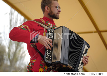 An accordion player in a national costume plays the accordion on the street. A young man with glasses is learning to play the accordion. The musician composes a new melody An accordion player in a national costume plays the accordion on the street. A young man with glasses is learning to play the accordion. The musician composes a new melody 140771096