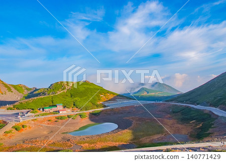 On a clear autumn day, a panoramic view of Tsurugaike Pond and the faintly visible Otani-dake mountain can be seen from the hiking trails of Norikura-dake and Fujimi-dake. On a clear autumn day, a panoramic view of Tsurugaike Pond and the faintly visible Otani-dake mountain can be seen from the hiking trails of Norikura-dake and Fujimi-dake. 140771429
