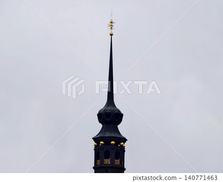 Historic Gothic tower with gilded ornamentation and slender profile standing tall amidst overcast atmosphere Historic Gothic tower with gilded ornamentation and slender profile standing tall amidst overcast atmosphere 140771463