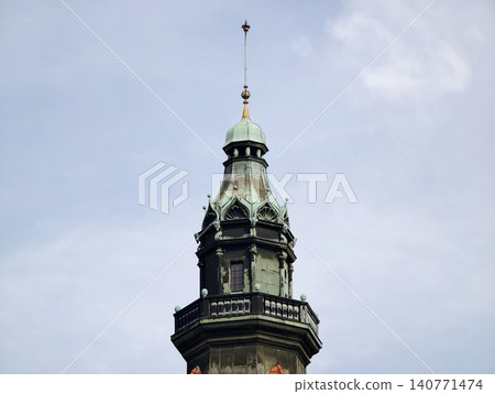 Ancient municipal tower adorned with gilded accents and layered spires visible against overcast sky 140771474