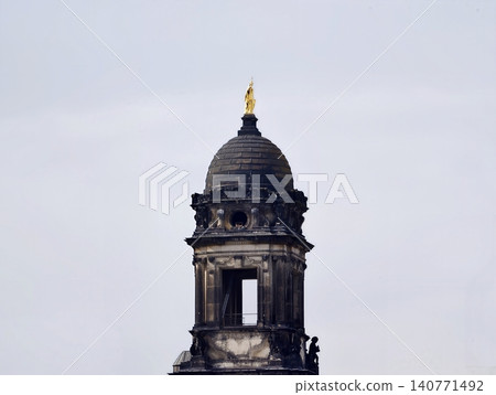 Weathered bell tower under cloudy sky. Historic stone steeple with archways and ornamental features Weathered bell tower under cloudy sky. Historic stone steeple with archways and ornamental features 140771492