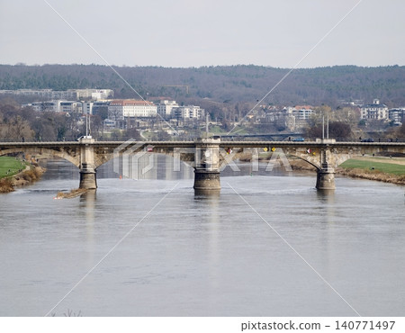 Tranquil river crossing with stone supports. Scenic view of old bridge with nature and structures Tranquil river crossing with stone supports. Scenic view of old bridge with nature and structures 140771497