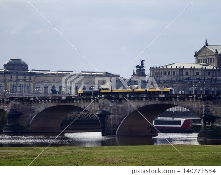 River scene showcasing busy urban transportation. Vibrant cityscape with tram crossing over river bridge 140771534