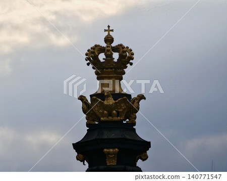 Golden crown outline. Ornate crown shape set against stormy skies with aged texture and dramatic lighting Golden crown outline. Ornate crown shape set against stormy skies with aged texture and dramatic lighting 140771547