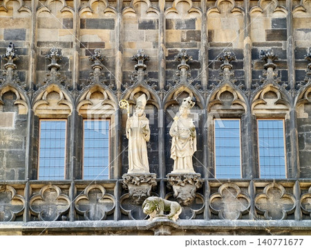 Ancient stone figures placed near intricate balustrades and reflective glass surfaces in city environments Ancient stone figures placed near intricate balustrades and reflective glass surfaces in city environments 140771677