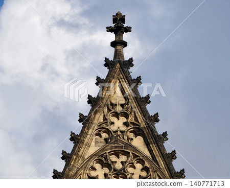 Elaborate gothic architectural ornamentation showcasing sculptural artistry against clear blue sky Elaborate gothic architectural ornamentation showcasing sculptural artistry against clear blue sky 140771713