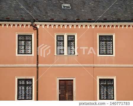 Pastel building with rhythmic windows. Repeating window frames and lace curtains create visual harmony Pastel building with rhythmic windows. Repeating window frames and lace curtains create visual harmony 140771783