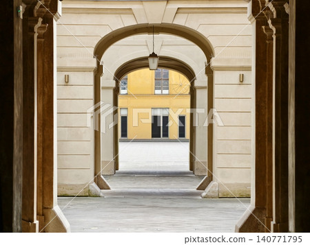 Sunlit arches surrounding peaceful courtyard. Symmetrical limestone arcades create tranquil ambiance Sunlit arches surrounding peaceful courtyard. Symmetrical limestone arcades create tranquil ambiance 140771795