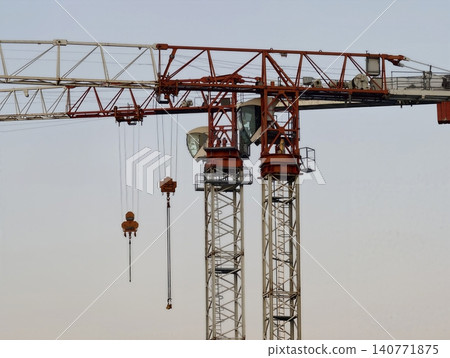 Massive cranes with steel arms reach high above construction zone as workers assemble structures Massive cranes with steel arms reach high above construction zone as workers assemble structures 140771875
