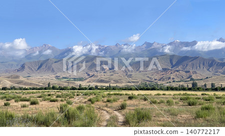 A breathtaking landscape overlooking the amazing mountains, hills and cliffs of Kyrgyzstan near Lake Issyk Kul. View of a rural dirt road. Travel and tourism. Trekking and hiking A breathtaking landscape overlooking the amazing mountains, hills and cliffs of Kyrgyzstan near Lake Issyk Kul. View of a rural dirt road. Travel and tourism. Trekking and hiking 140772217