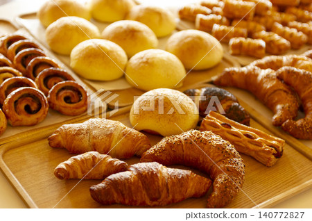 A rich selection of freshly baked breads displayed on wooden boards in the bakery. A rich selection of freshly baked breads displayed on wooden boards in the bakery. 140772827