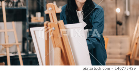 Female artist wears black hat posing near picture indoor the studio Female artist wears black hat posing near picture indoor the studio 140773459