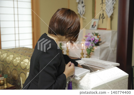 A woman mourns the passing of the deceased at a funeral. A woman mourns the passing of the deceased at a funeral. 140774400