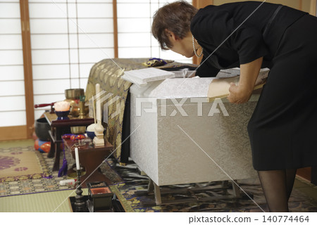 A woman mourns the passing of the deceased at a funeral. A woman mourns the passing of the deceased at a funeral. 140774464