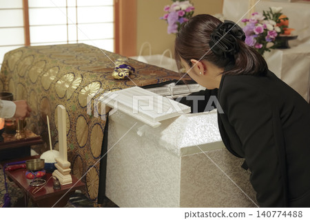 A woman mourns the passing of the deceased at a funeral. 140774488