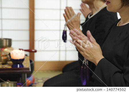 Family members offer prayers for the deceased, holding prayer beads. Family members offer prayers for the deceased, holding prayer beads. 140774502