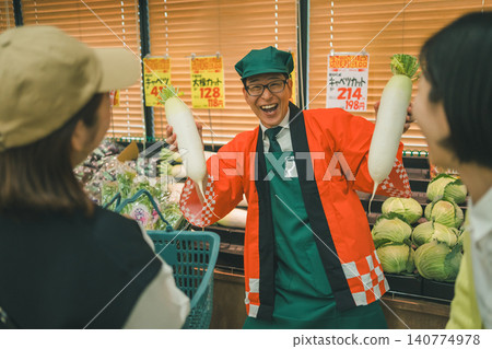 一位笑容滿面的超市員工舉著一個蘿蔔。 一位笑容滿面的超市員工舉著一個蘿蔔。 140774978