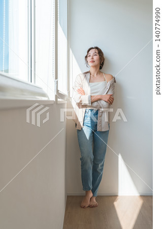 一位女性(模特,時尚人士)站在陽光灑滿的窗邊。 一位女性(模特,時尚人士)站在陽光灑滿的窗邊。 140774990