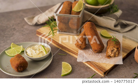 Crispy golden croquettes served with dipping sauce and lime wedges Crispy golden croquettes served with dipping sauce and lime wedges 140775017