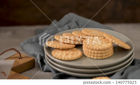 Round Cracker Biscuits stacked on a Ceramic Plate 140775025