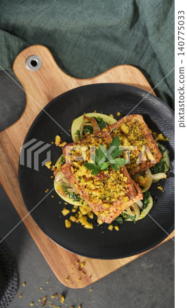 Baked tofu steak with herb breadcrumb crust over sauteed greens Baked tofu steak with herb breadcrumb crust over sauteed greens 140775033