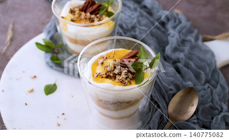 Delicious yogurt parfait with mango puree and pecans Delicious yogurt parfait with mango puree and pecans 140775082