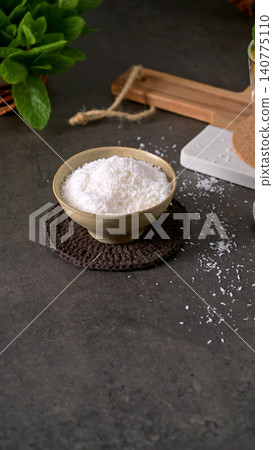 Fine Desiccated Coconut Shavings in a Ceramic Bowl on a Dark Textured Table Fine Desiccated Coconut Shavings in a Ceramic Bowl on a Dark Textured Table 140775110