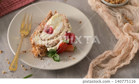 A slice of sweet meringue roll cake with cream and fresh berries on a plate A slice of sweet meringue roll cake with cream and fresh berries on a plate 140775116