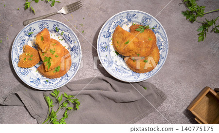 Fried Golden Empanadas with Fresh Parsley on Blue Patterned Plates Fried Golden Empanadas with Fresh Parsley on Blue Patterned Plates 140775175