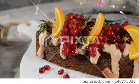 A festive loaf cake decorated with orange slices, red currants, and rosemary sprigs, drizzled with a creamy frosting and sprinkled with cinnamon A festive loaf cake decorated with orange slices, red currants, and rosemary sprigs, drizzled with a creamy frosting and sprinkled with cinnamon 140775338
