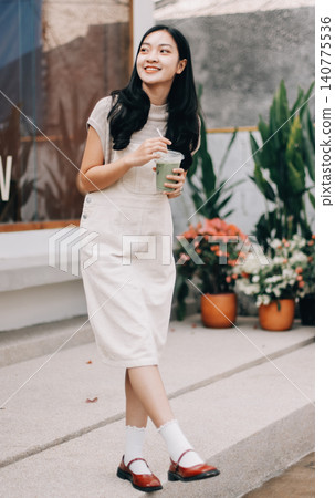 Young woman drinking iced coffee outside a chocolate shop Young woman drinking iced coffee outside a chocolate shop 140775536