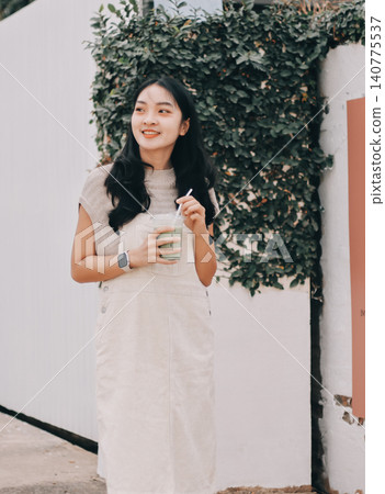Young woman drinking iced coffee outside a chocolate shop Young woman drinking iced coffee outside a chocolate shop 140775537